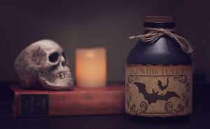 A fake skull, candle, book, and potion being used as Halloween apartment decor.